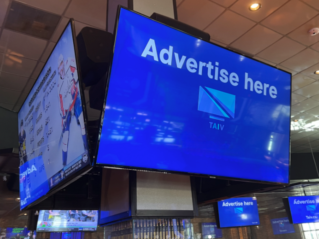 Venue advertising displayed on multiple screens inside a bar or restaurant